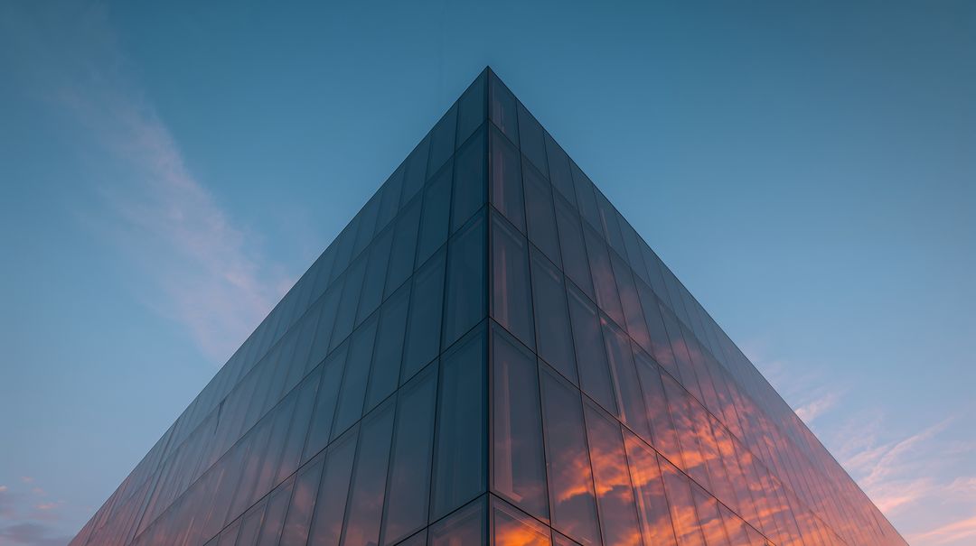 Glass Apex Reflecting Vibrant Sunset Clouds on Geometric Facade