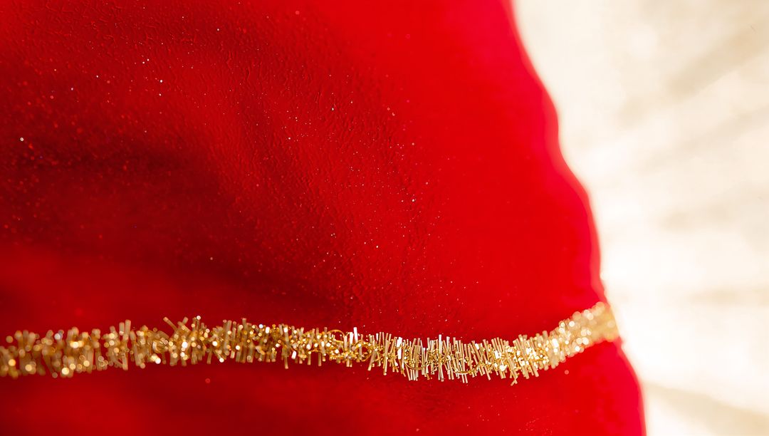 Macro red velvet fabric with sparkling gold tinsel and glitter creating festive luxury