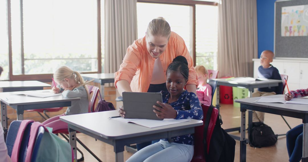 Teacher Guiding Young Student on Tablet in a Classroom