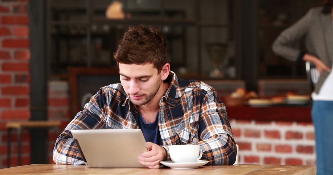 Young Man Using Tablet at Cozy Cafe - Free Images, Stock Photos and Pictures on Pikwizard.com