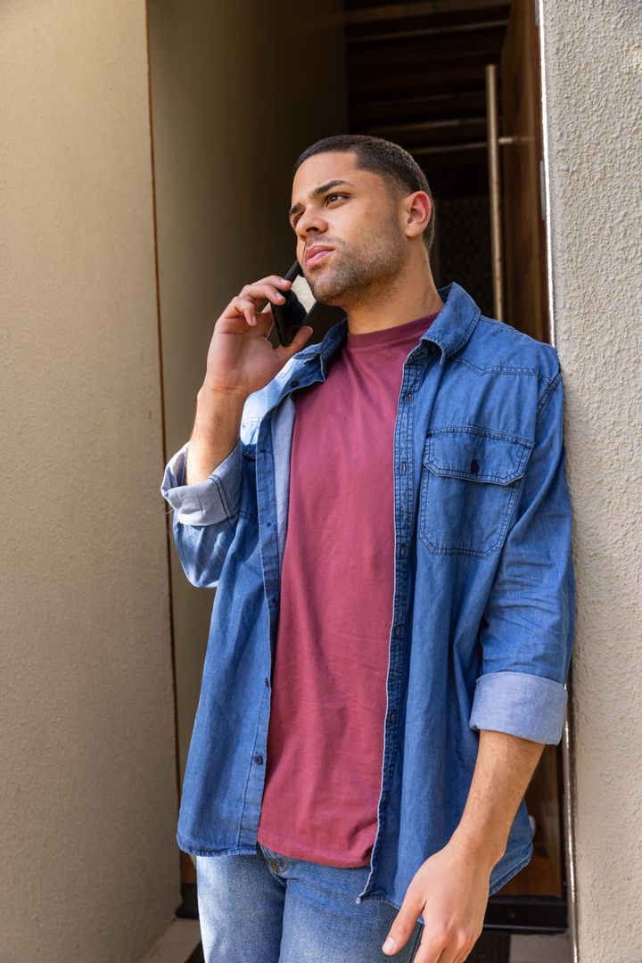 Young Man Leaning in Corridor Talking on Smartphone