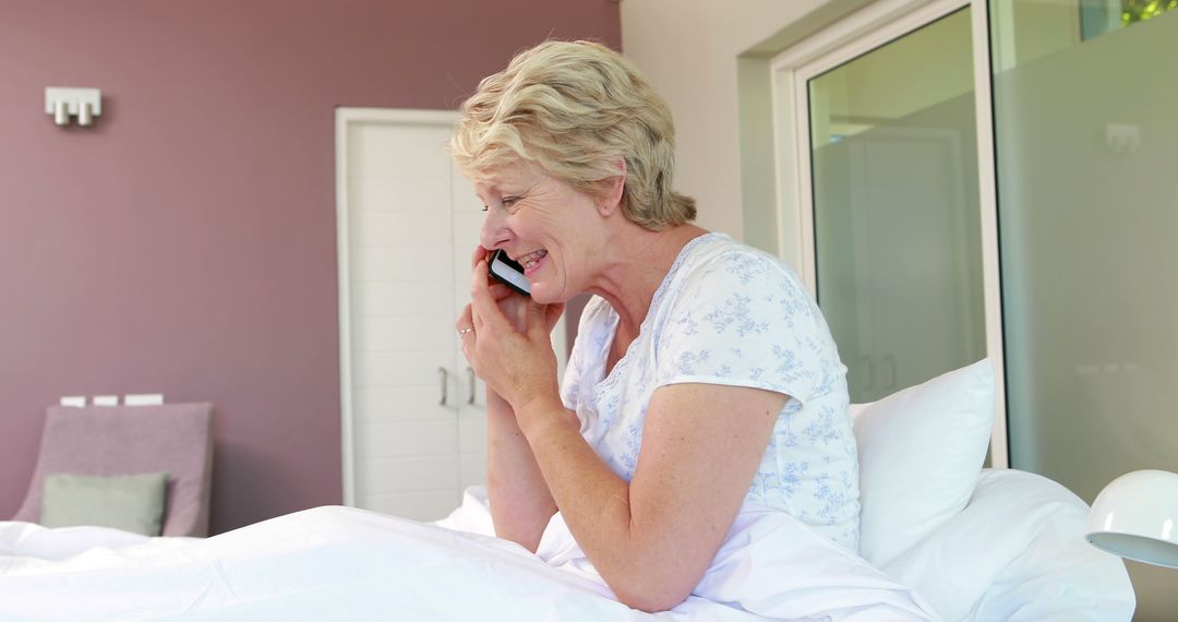 Elderly Woman Talking Happily on Phone in Cozy Bedroom - Free Images, Stock Photos and Pictures on Pikwizard.com