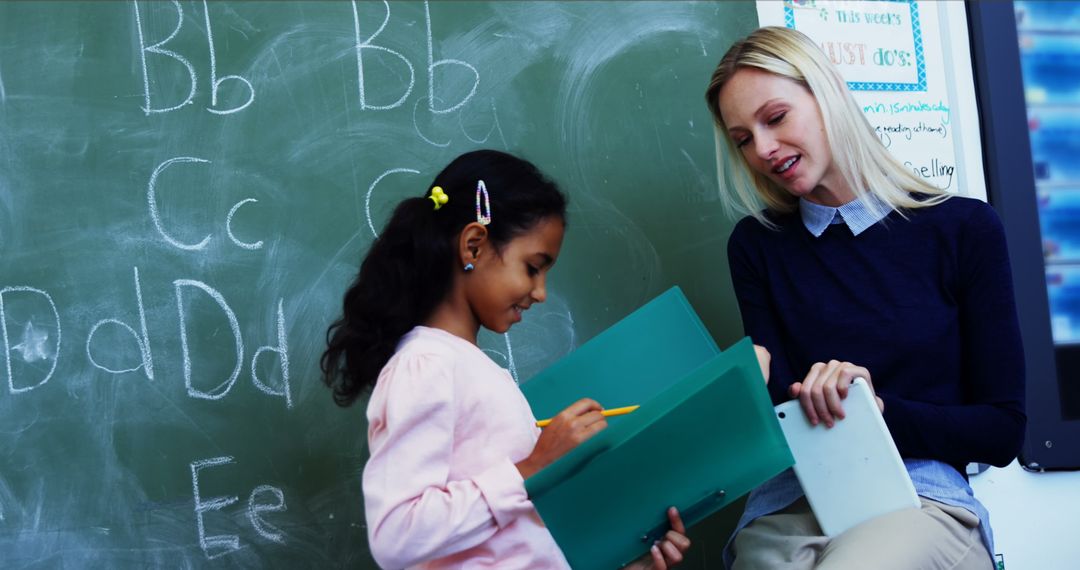 Engaged Teacher Kan Communicating with Biracial Student in Classroom Setting