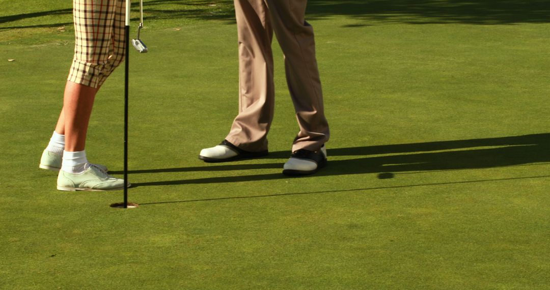 Golfers on Green Near Hole with Shadows on Grass - Free Images, Stock Photos and Pictures on Pikwizard.com