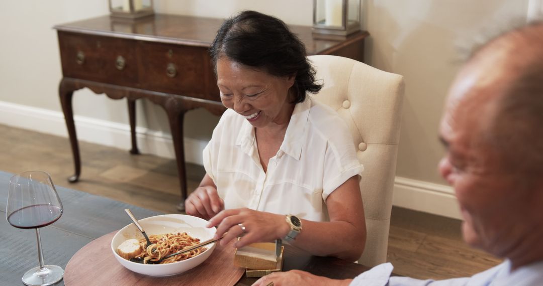 Asian Senior Couple Enjoying Pasta Dinner with Wine at Home