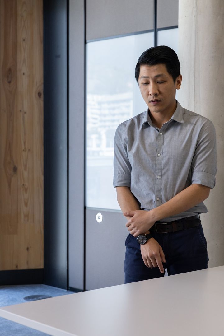 Professional Asian Man Checking Time in Urban Office Setting
