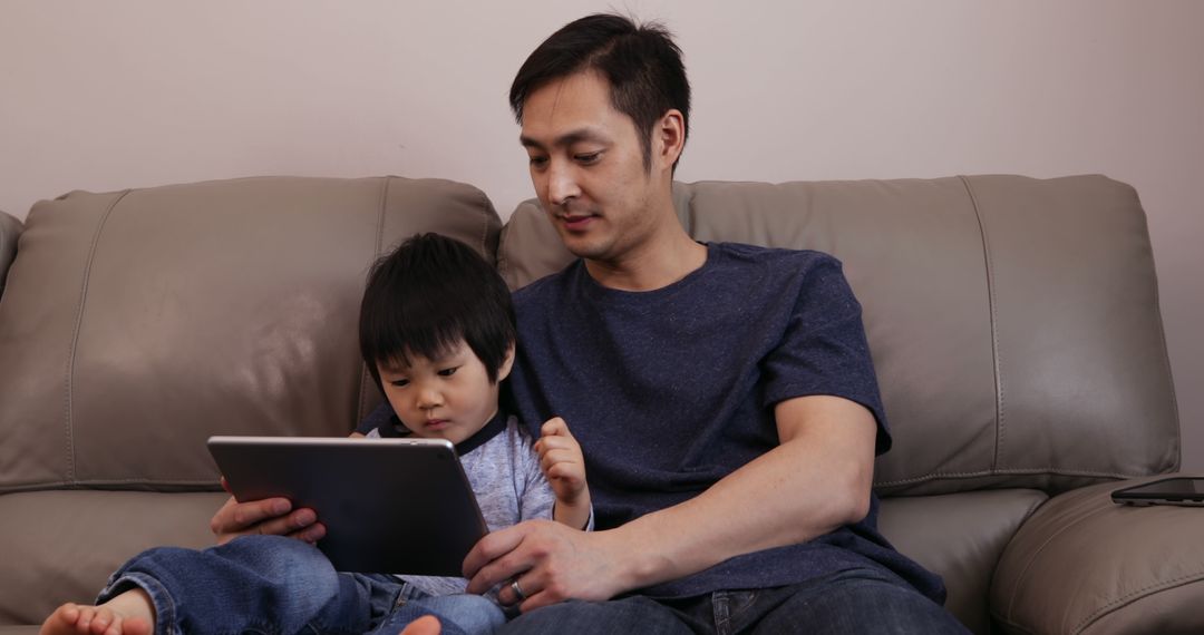 Father Sitting on Couch with Child Using Tablet - Free Images, Stock Photos and Pictures on Pikwizard.com