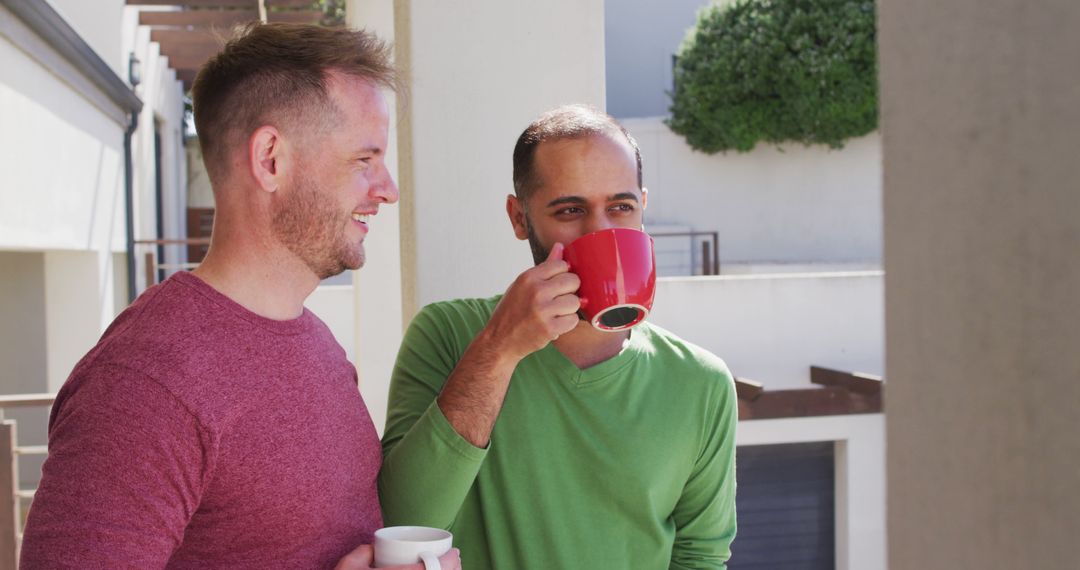 Two men enjoying coffee on balcony while conversing - Free Images, Stock Photos and Pictures on Pikwizard.com