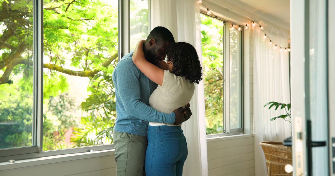 Romantic Couple Embracing in Sunlit Room with Large Windows