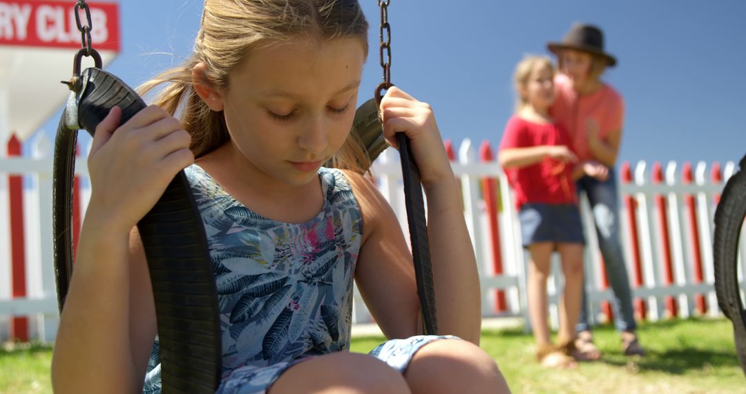 Sad Girl on Swing at Playground While Friends Interact in Background - Free Images, Stock Photos and Pictures on Pikwizard.com