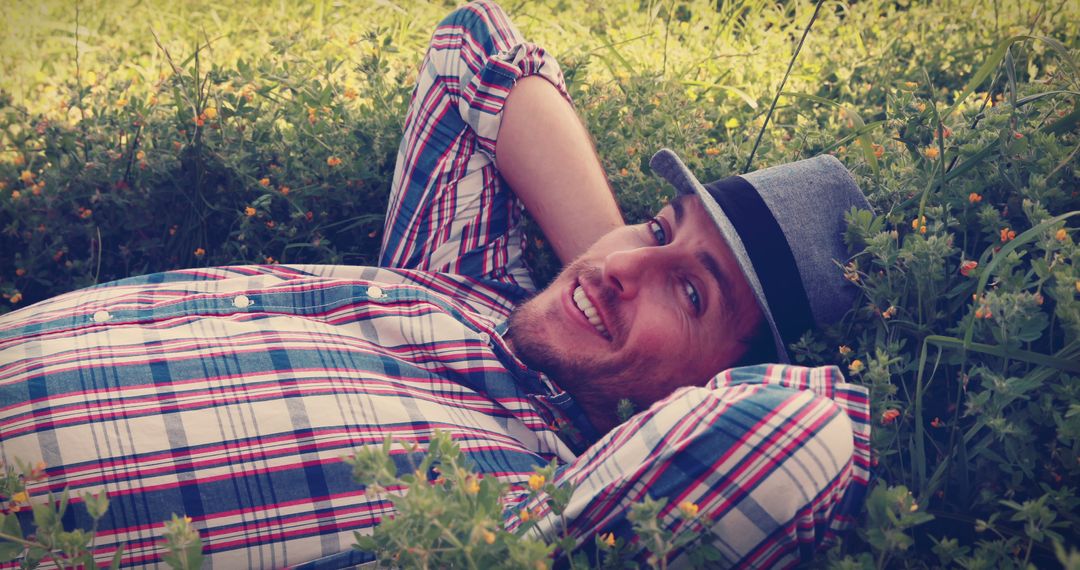 Man Smiling Relaxing in Wildflowers Wearing Plaid and Hat - Free Images, Stock Photos and Pictures on Pikwizard.com