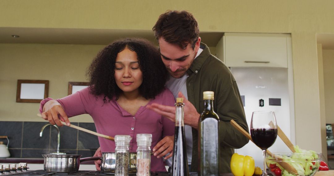 Happy Multiethnic Couple Embracing While Cooking Together in Kitchen - Free Images, Stock Photos and Pictures on Pikwizard.com