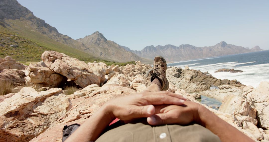 Person Relaxing on Rocky Coastline with Mountain View - Free Images, Stock Photos and Pictures on Pikwizard.com