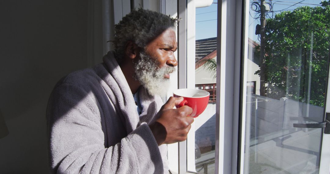 Elderly Man in Robe Sipping Coffee by Window in Bright Morning Light - Free Images, Stock Photos and Pictures on Pikwizard.com