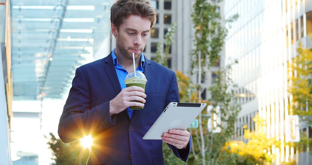 Businessman Enjoying Smoothie while Working on Tablet in Urban Environment - Free Images, Stock Photos and Pictures on Pikwizard.com