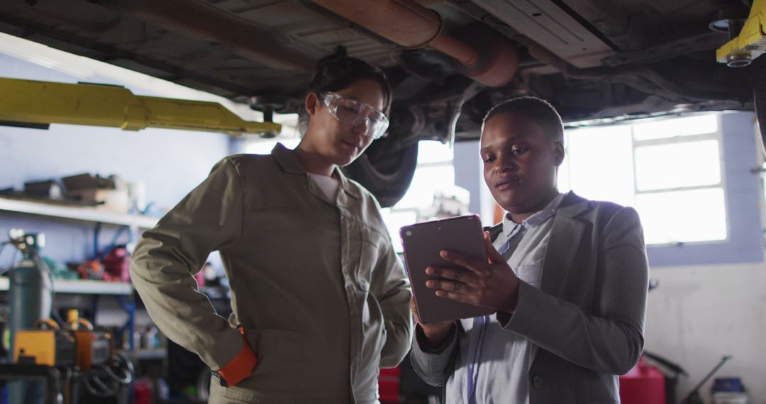 Image of two diverse female car mechanic and business owner with tablet checking car - Free Images, Stock Photos and Pictures on Pikwizard.com