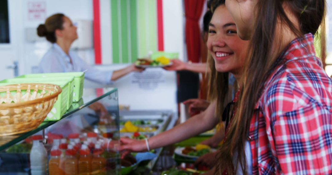 A cheerful young Asian woman enjoys choosing food at a buffet with diverse staff. - Free Images, Stock Photos and Pictures on Pikwizard.com