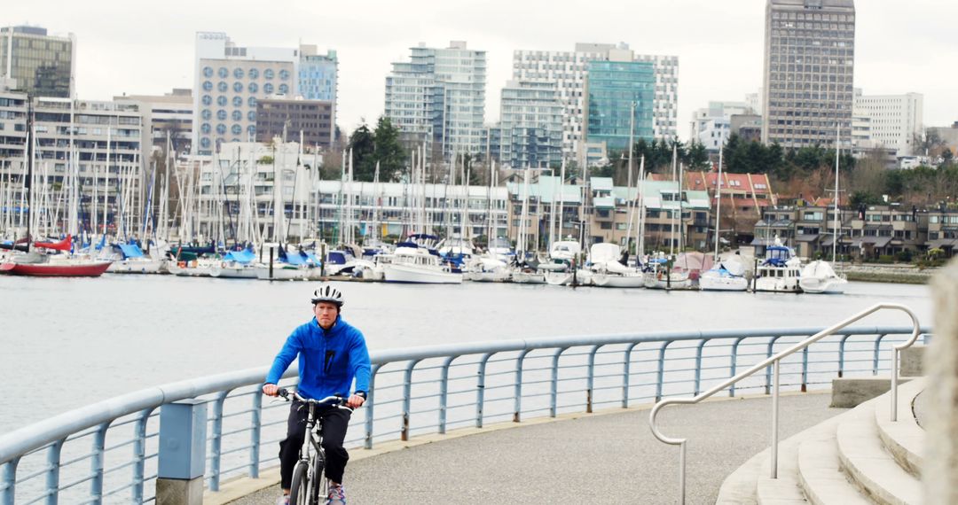 Man Cycling along Urban Waterfront Pathway with City Skyline - Free Images, Stock Photos and Pictures on Pikwizard.com