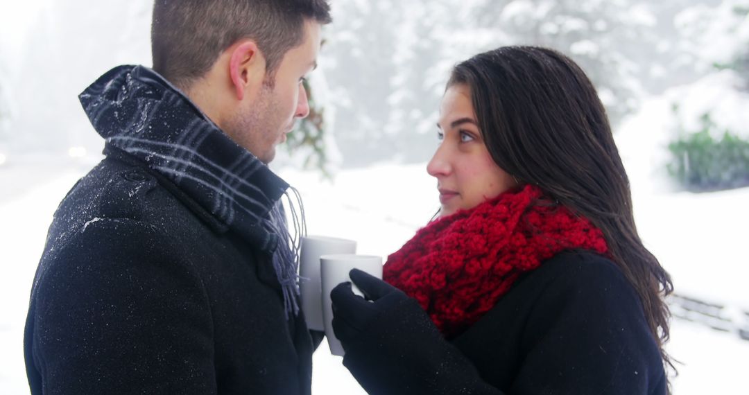 Young couple enjoying hot drinks on snowy winter day - Free Images, Stock Photos and Pictures on Pikwizard.com