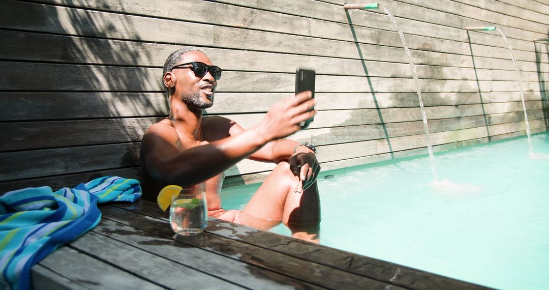 Stylish Man Relaxing By Poolside Taking Selfie on Sunny Day