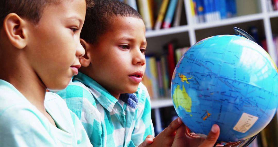 Two Curious Children Studying Globe in Library - Free Images, Stock Photos and Pictures on Pikwizard.com