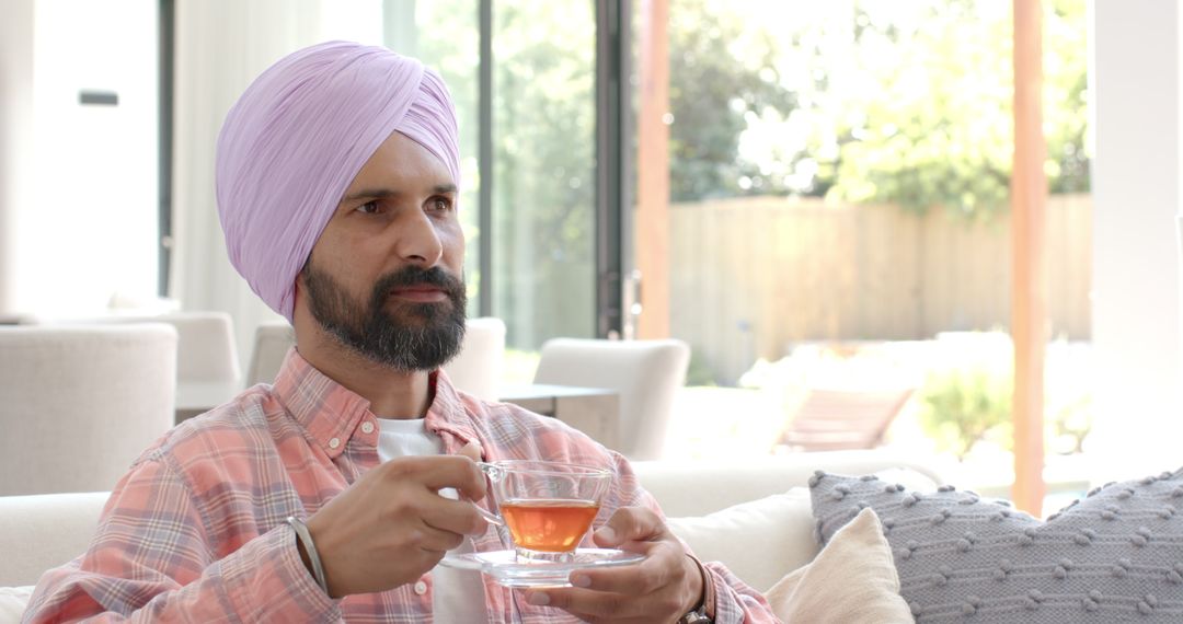 Man in Turban Sipping Tea on Sofa, Embracing Indian Tradition