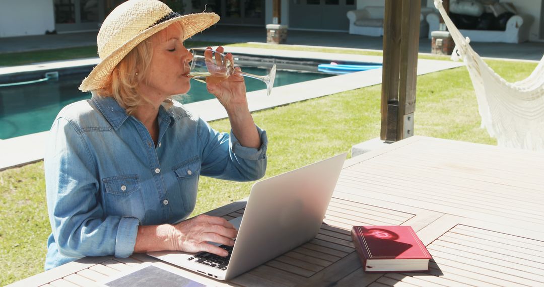 Senior Woman Relaxing by Pool on Laptop and Drinking Wine - Free Images, Stock Photos and Pictures on Pikwizard.com