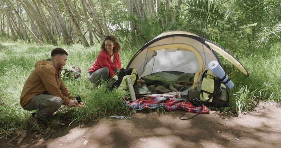 Young Couple Setting Up Tent in Lush Forest - Free Images, Stock Photos and Pictures on Pikwizard.com