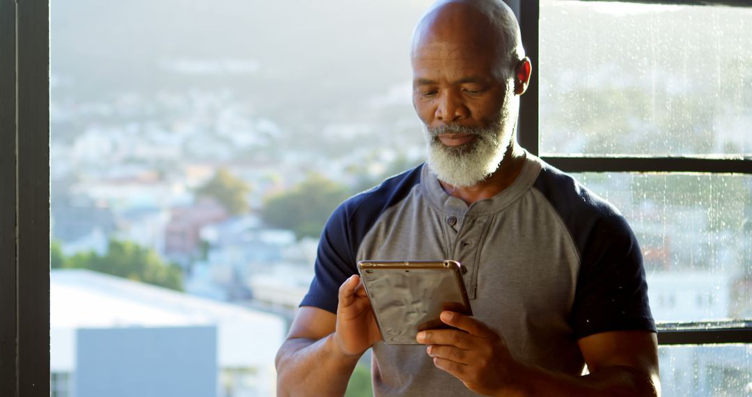 Middle-aged African American Man Using Digital Tablet by Window - Free Images, Stock Photos and Pictures on Pikwizard.com