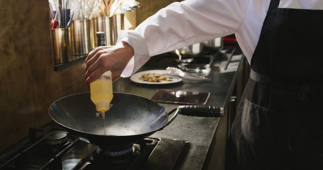 Close-Up of Chef Adding Oil to Pan in Professional Kitchen - Free Images, Stock Photos and Pictures on Pikwizard.com