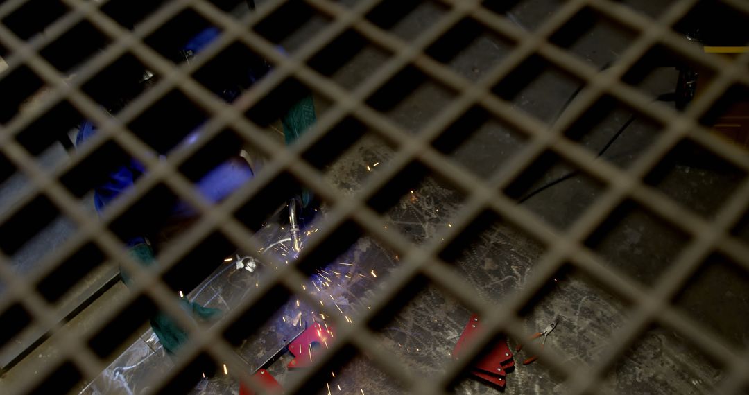 Metalworker Welding Behind Protective Grate with Spark Showers - Free Images, Stock Photos and Pictures on Pikwizard.com