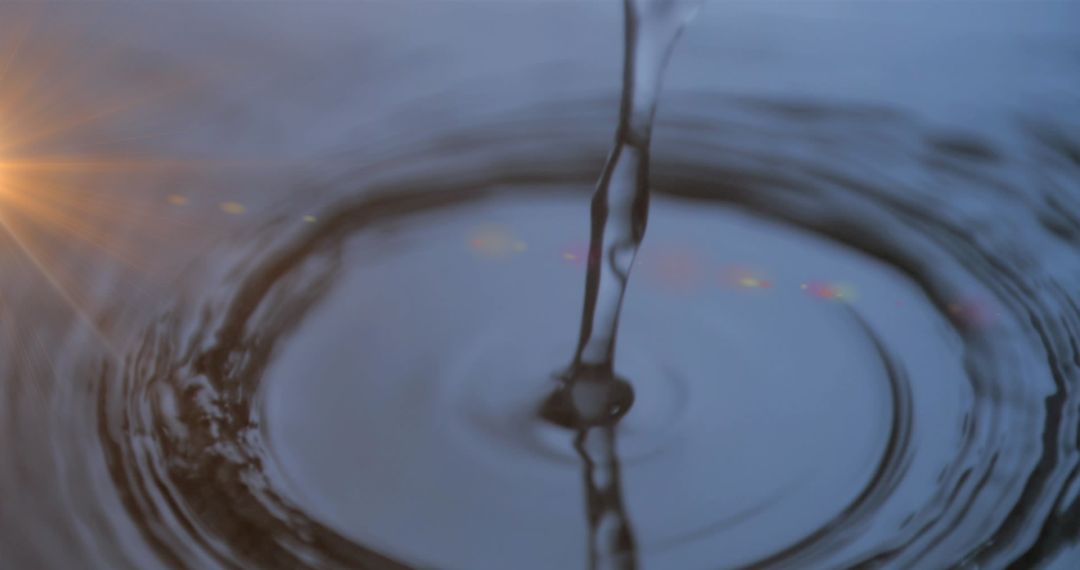 Water drop creating ripples with sunlight lens flare
