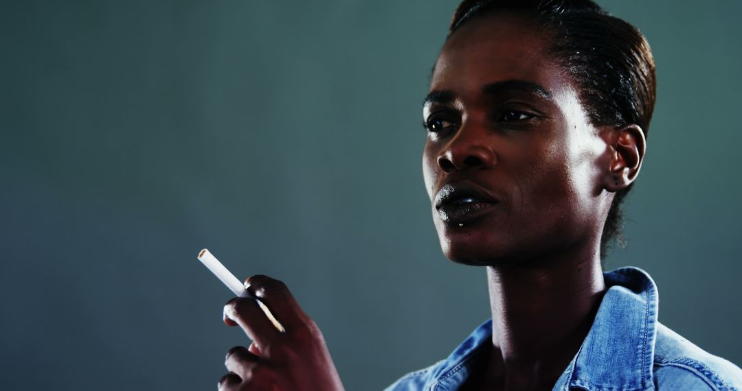 Pensive African American Woman Smoking in Denin Shirt against Gray Background - Free Images, Stock Photos and Pictures on Pikwizard.com