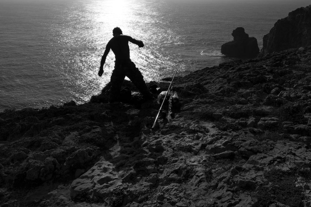 Silhouette of Man Fishing on Rocky Cliff During Sunset by Ocean - Free Images, Stock Photos and Pictures on Pikwizard.com