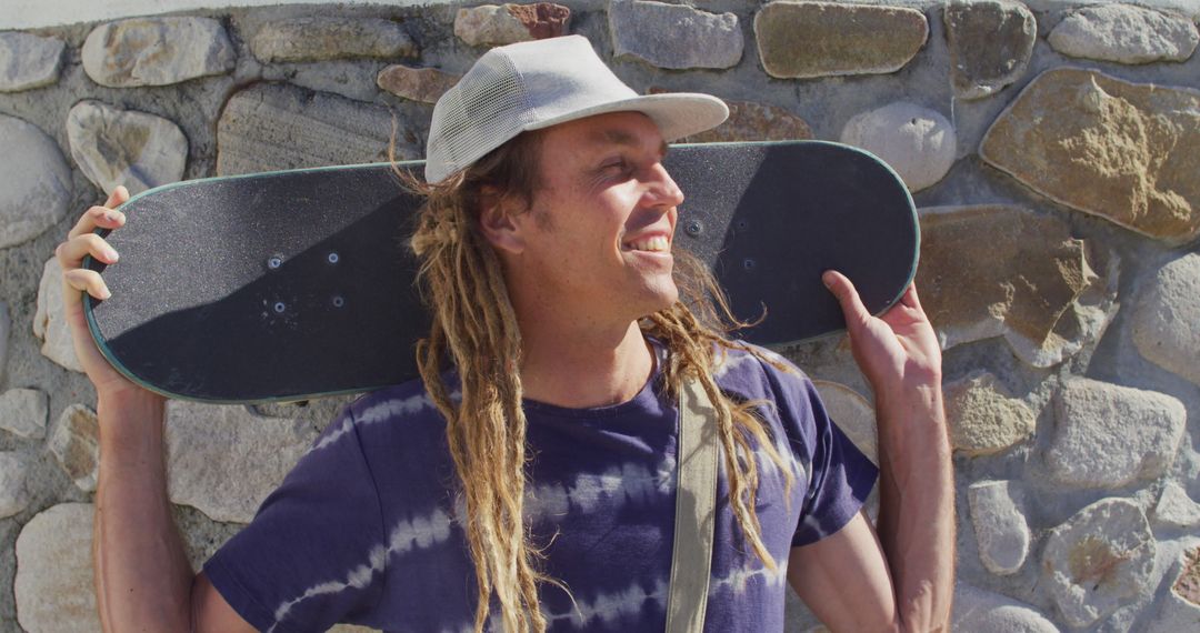 Man with Dreadlocks Holding Skateboard Smiling Outdoors - Free Images, Stock Photos and Pictures on Pikwizard.com