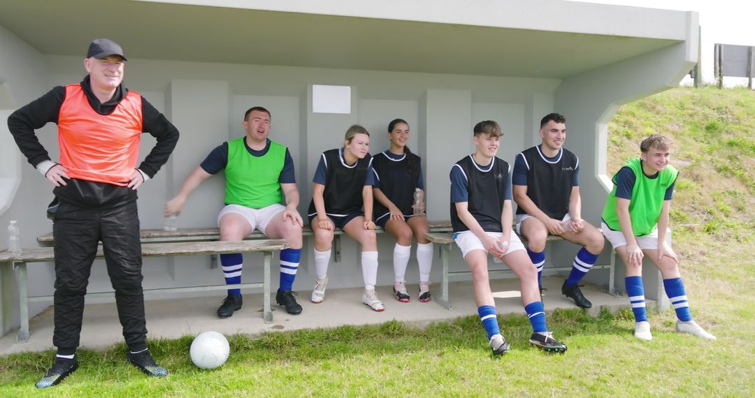 Soccer Team Resting on Sidelines with Coach at Training Session