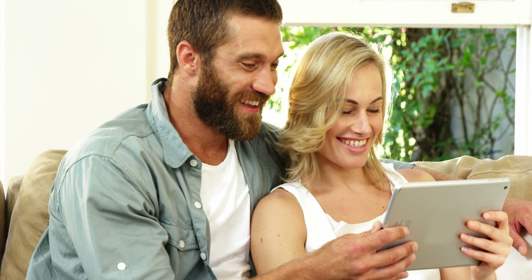 Joyful Couple Using Tablet Together on Cozy Sofa