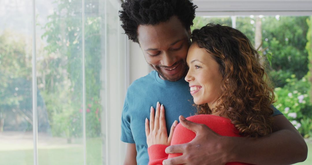 Happy Couple Embracing by Window in Sunlit Home