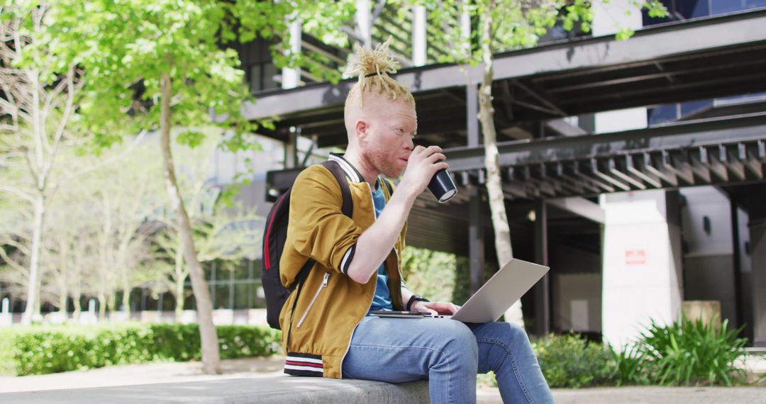 Young Man with Backpack Using Laptop And Drinking Coffee Outdoors - Free Images, Stock Photos and Pictures on Pikwizard.com