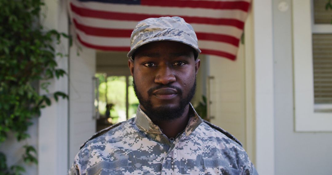 Portrait of african american male soldier standing in front of house and american flag - Free Images, Stock Photos and Pictures on Pikwizard.com