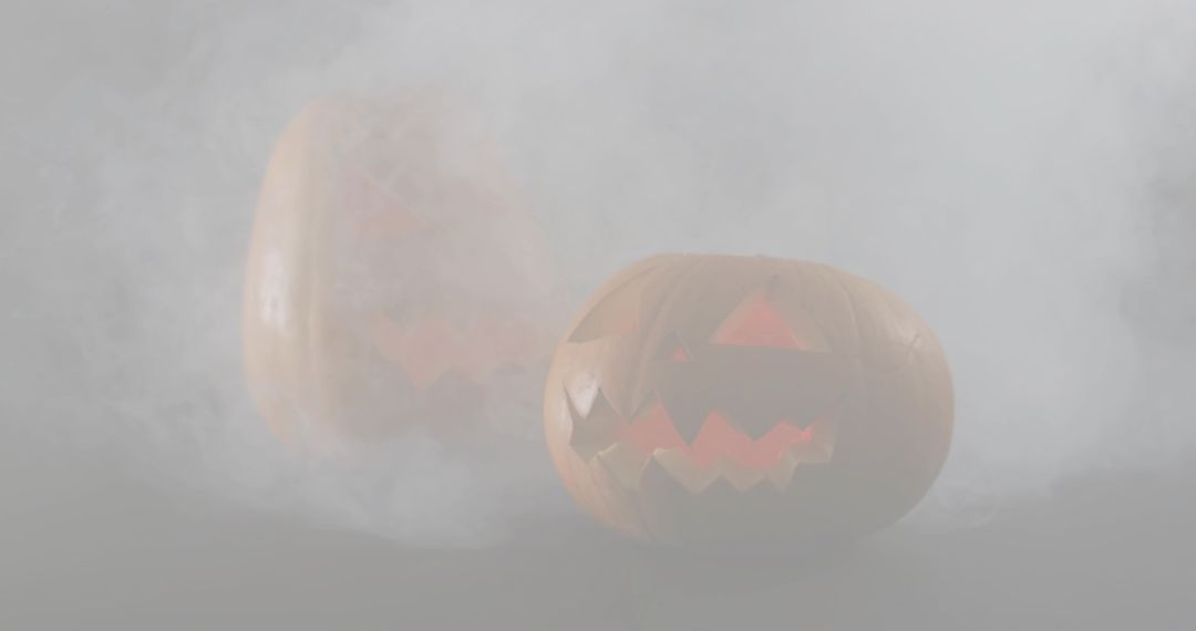 Glowing jack-o-lanterns in fog casting warm orange reflection on glossy moody surface
