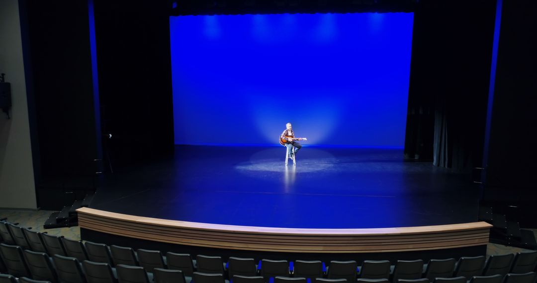 Solo Guitarist Performing on Stage with Blue Lighting in Theater - Free Images, Stock Photos and Pictures on Pikwizard.com