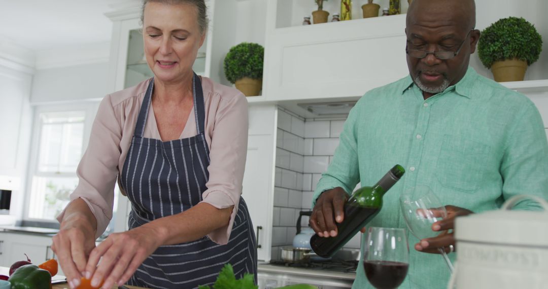 Smiling Senior Couple Cooking and Enjoying Wine in Home Kitchen