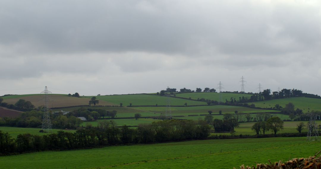Cloudy Rural Landscape with Electricity Pylons and Farmland - Free Images, Stock Photos and Pictures on Pikwizard.com