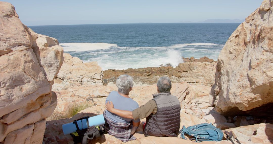 Back view of diverse senior couple sitting on rocks and looking at sea - Free Images, Stock Photos and Pictures on Pikwizard.com