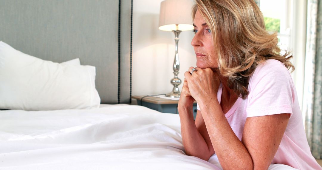 Pensive Mature Woman Sitting on Bed in Bedroom - Free Images, Stock Photos and Pictures on Pikwizard.com