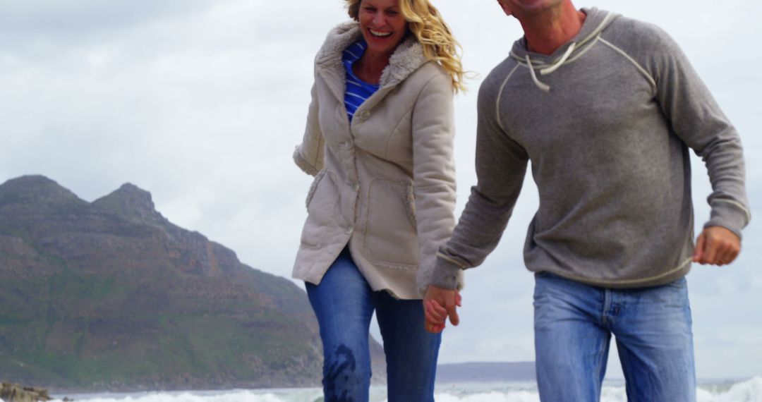 Joyful Middle-Aged Couple Walking by the Seashore - Free Images, Stock Photos and Pictures on Pikwizard.com