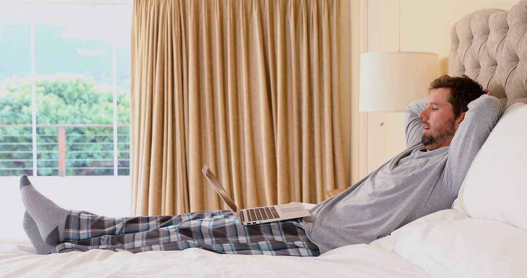 Man Relaxing in Bed Using Laptop Wearing Pajamas - Free Images, Stock Photos and Pictures on Pikwizard.com