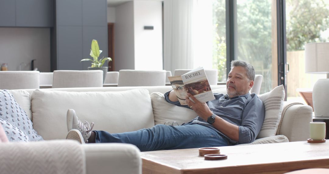 Senior man relaxing on sofa reading magazine in modern living room - Free Images, Stock Photos and Pictures on Pikwizard.com