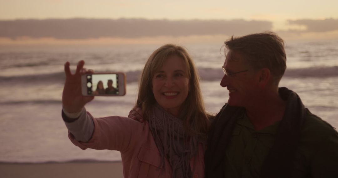 Smiling Couple Taking Selfie at Beach Sunset - Free Images, Stock Photos and Pictures on Pikwizard.com